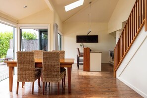 Un comedor amplio con una mesa de madera y sillas de mimbre, una cocina con una isla de madera y una escalera con barandillas de madera.