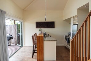 Una cocina moderna con una isla central, un comedor con sillas y vistas al exterior.