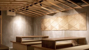 Un interior moderno con bancos de madera y un tapiz mural geométrico.