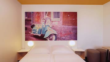 Una habitación de hotel con una cama, mesitas de noche y un cuadro colgado en la pared de una moto antigua.