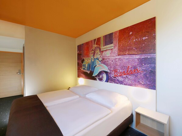 Ein Hotelzimmer mit einem Bett, einem Wandbild einer Oldtimer-Limousine und einer Tür.