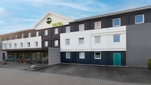 Een modern hotel met een plat dak, meerdere ramen en een verhard entreegebied.