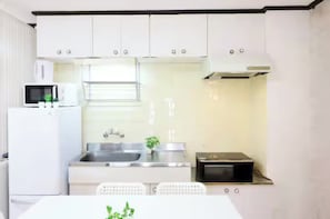Una cocina moderna con armarios blancos, un lavamanos de acero inoxidable, un microondas y un tostador.