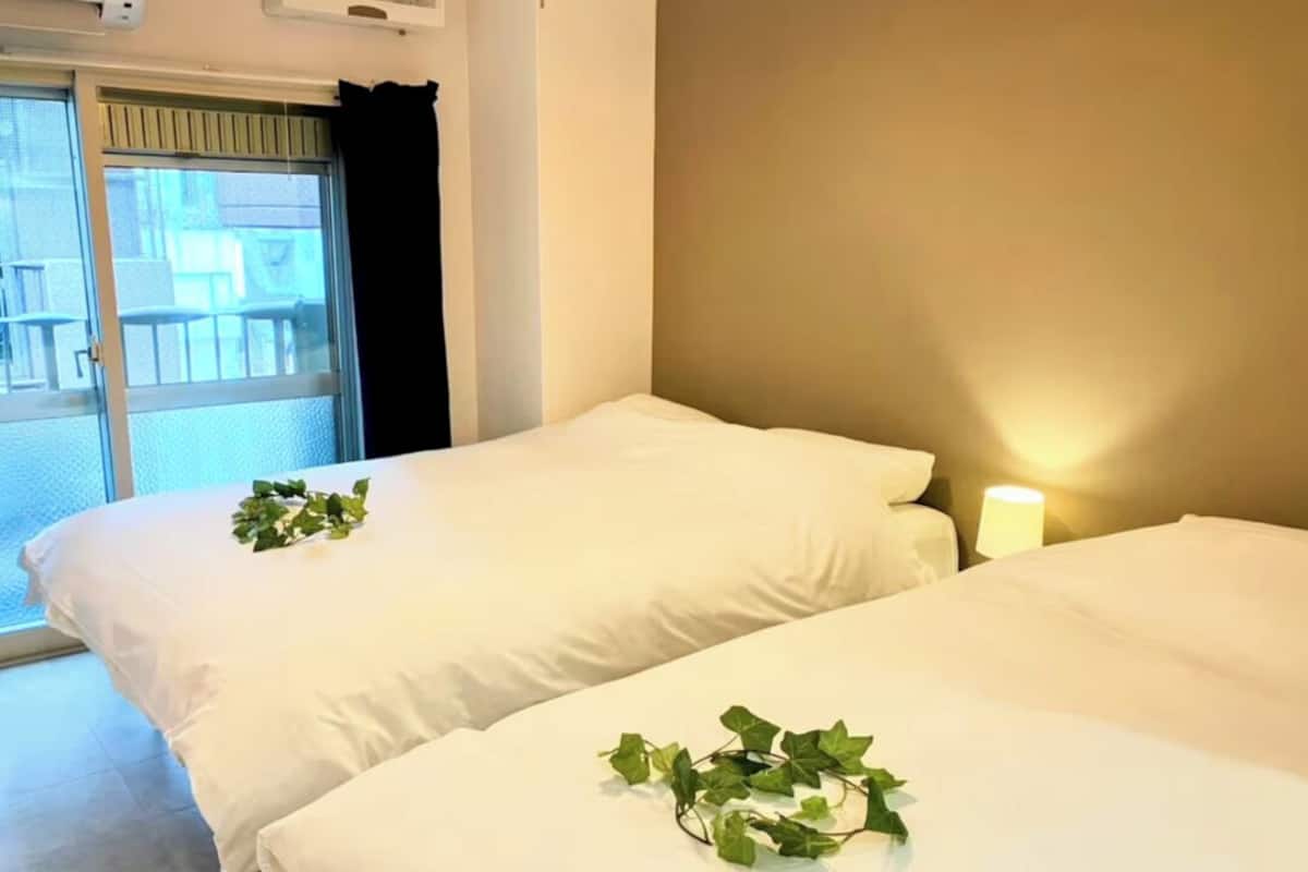 A hotel room with two beds, a window with a view, and a nightstand with a lamp.