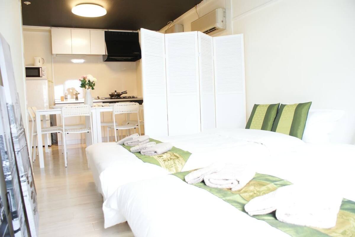 A hotel room with a bed, a desk, a chair, and a kitchenette.