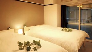A hotel room with two beds, a bedside table with a lamp, and a window with a view of a balcony. - Shin-Osaka GRAND (Osaka)
