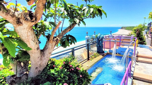 A pool area with a view of the ocean, surrounded by greenery and a staircase leading to a terrace. - Hotel Moon (Xincheng)