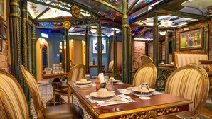 A dining area with ornate chairs, a long wooden table, and a chandelier. - Hotel Moon (Xincheng)
