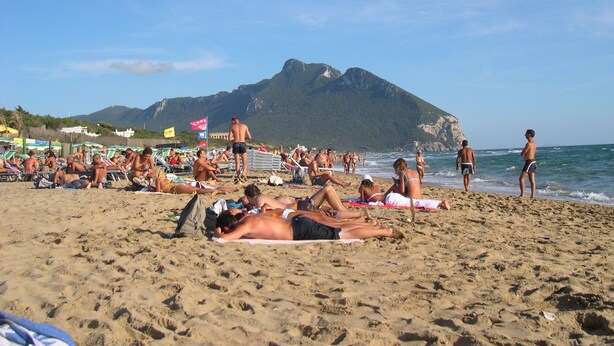 A crowded beach with people sunbathing and swimming, a mountain in the background, and beach umbrellas. - villa in the center of sabaudia sleeps 6 (Sabaudia)