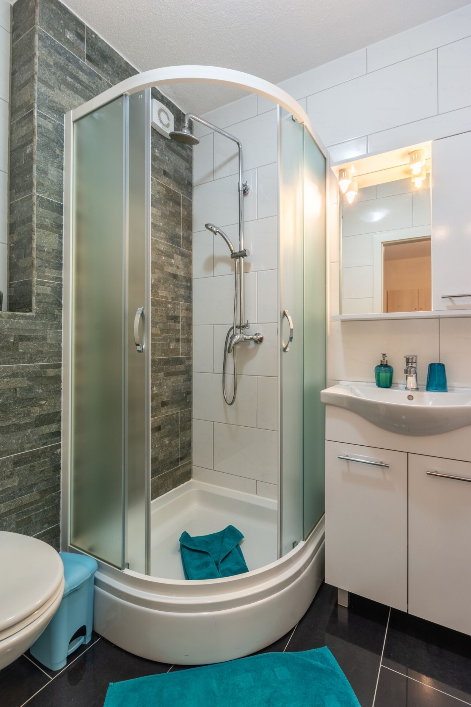 A modern bathroom with a glass-enclosed shower, a white sink, and a mirror above the sink.