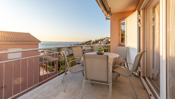 A balcony with a table and chairs, overlooking a coastal view. - Apartments Palma (Omis)