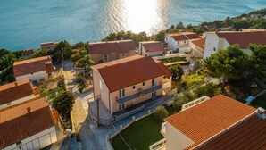 A coastal residential area with houses featuring red-tiled roofs and a view of the sea. - Apartments Palma (Omis)