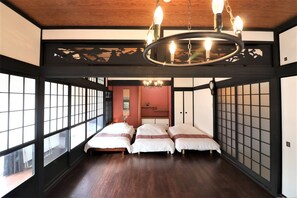 A traditional Japanese-style room with tatami flooring, shoji screens, and a central bed with a hanging light fixture. - Residential Hotel Osaka chikko OC (Osaka)