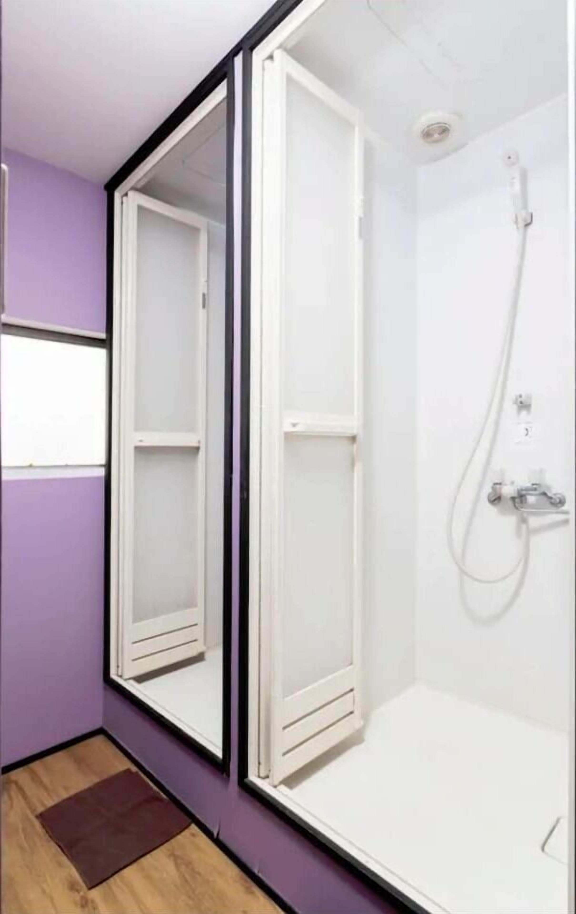 A bathroom with a shower, a mirror, and a wooden floor.