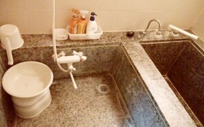Een badkamer met een wastafel, toilet en douche. Er staan toiletartikelen op het aanrecht.