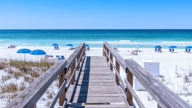 A wooden boardwalk leading to a beach with blue umbrellas and beach chairs. - Modern Townhome, Short Walk to Beach w/ Private Access, Pool & Grill (Destin)