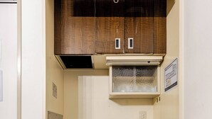 Una kitchenette compacta con armarios de madera, un lavamanos de acero inoxidable y un refrigerador pequeño.