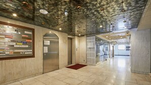 Un interior moderno con suelo de mármol, una puerta de cristal e iluminación empotrada en el techo.
