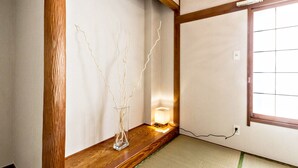 A traditional Japanese room with tatami flooring, a wooden beam, a shoji screen, and a vase with branches. - Ikebukuro Yamase Building GR1 (Tokyo)