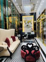 Un vestíbulo de hotel con una recepción, un sofá, un pouf decorativo y una araña.