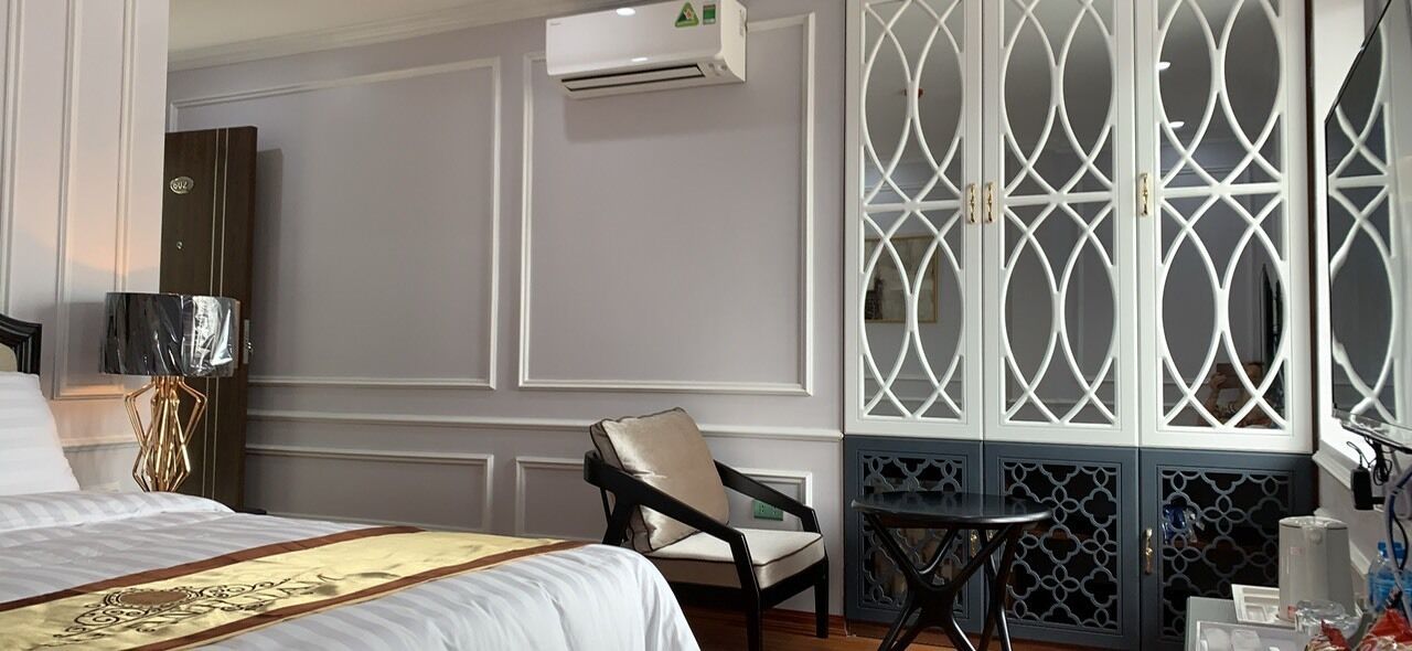 Una habitación de hotel con cama, una silla, una mesita y un biombo decorativo.