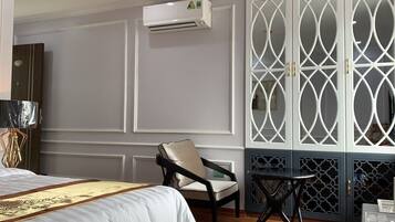 Una habitación de hotel con cama, una silla, una mesita y un biombo decorativo.