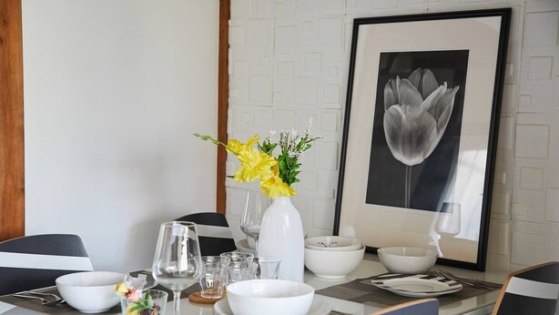 A dining table set with white plates, bowls, and glasses, accompanied by a vase of yellow flowers. - RESIDENTIAL HOTEL DAIICHI-H SHIN-OKUBO Room.A (Tokyo)