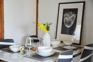 A dining table set with white plates, bowls, and glasses, accompanied by a vase of yellow flowers. - RESIDENTIAL HOTEL DAIICHI-H SHIN-OKUBO Room.A (Tokyo)