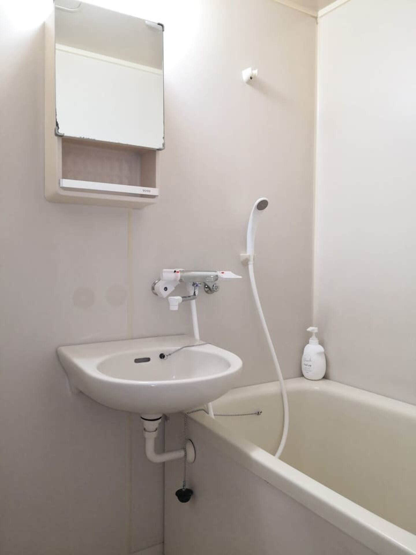 A bathroom with a white sink, a mirror, and a bathtub.