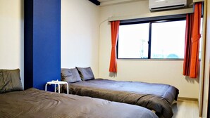 Ein Hotelzimmer mit zwei Betten, einem kleinen Tisch und einem Fenster mit Vorhängen.