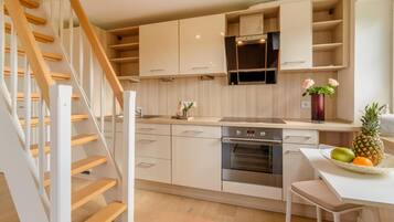 Eine moderne Küche mit Holzausstattung, einem eingebauten Ofen und einem Essbereich mit Tisch und Stühlen.