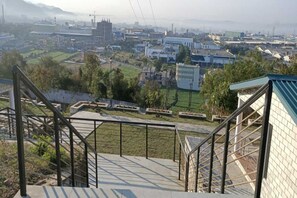 A staircase leading to a building with a view of a cityscape in the background. - Turquoise Resort (Nalagarh)