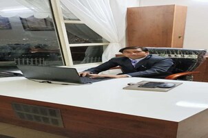 Un hombre sentado en un escritorio con una computadora portátil, un ratón y un cuaderno.