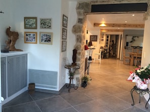 A spacious living area with a stone wall, a fireplace, and a dining area in the background. - Large family home, swimming pool, jacuzzi, pool house, boules court (CHATEAUNEUF)