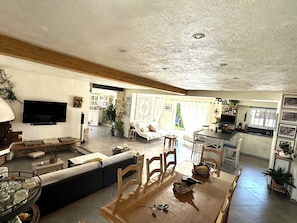 A spacious living area with a sofa, dining table, and kitchen in the background.