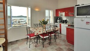 A kitchen with a dining table, chairs, a refrigerator, and a TV. - 50m from the beach, 2 apartments side by side, sea view, tip of the Giens peninsula (Hyères)