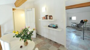 A modern living room with a white sofa, a coffee table with flowers, a bookshelf, and a dining area with a chair and table. - 50m from the beach, 2 apartments side by side, sea view, tip of the Giens peninsula (Hyères)