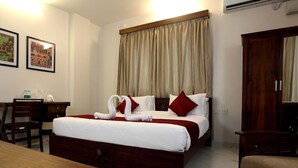 Una camera d'albergo con un letto, una scrivania e due sedie. In parete, due quadri incorniciati.
