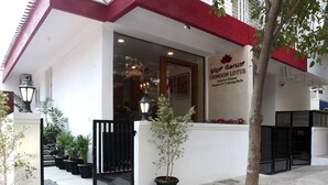 Un edificio con facciata rossa e bianca, un cartello con la scritta “CRIMSON LOTUS Superior Rooms” e un ingresso chiuso da un cancello.