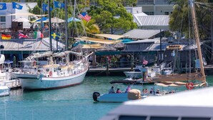 Un puerto deportivo con varias embarcaciones amarradas, algunas con banderas, y un edificio con balcón al fondo.