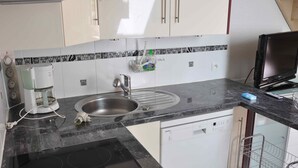 A kitchen with a built-in dishwasher, a coffee maker, and a sink with a faucet.
