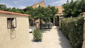 A courtyard with a tiled floor, outdoor seating, and a wall-mounted light fixture.