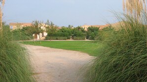 A gravel path leading to a green lawn area with buildings in the background.