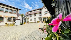 A courtyard with a paved walkway, outdoor seating, and a staircase leading to a building. - Pensiunea Luiza (Brasov)