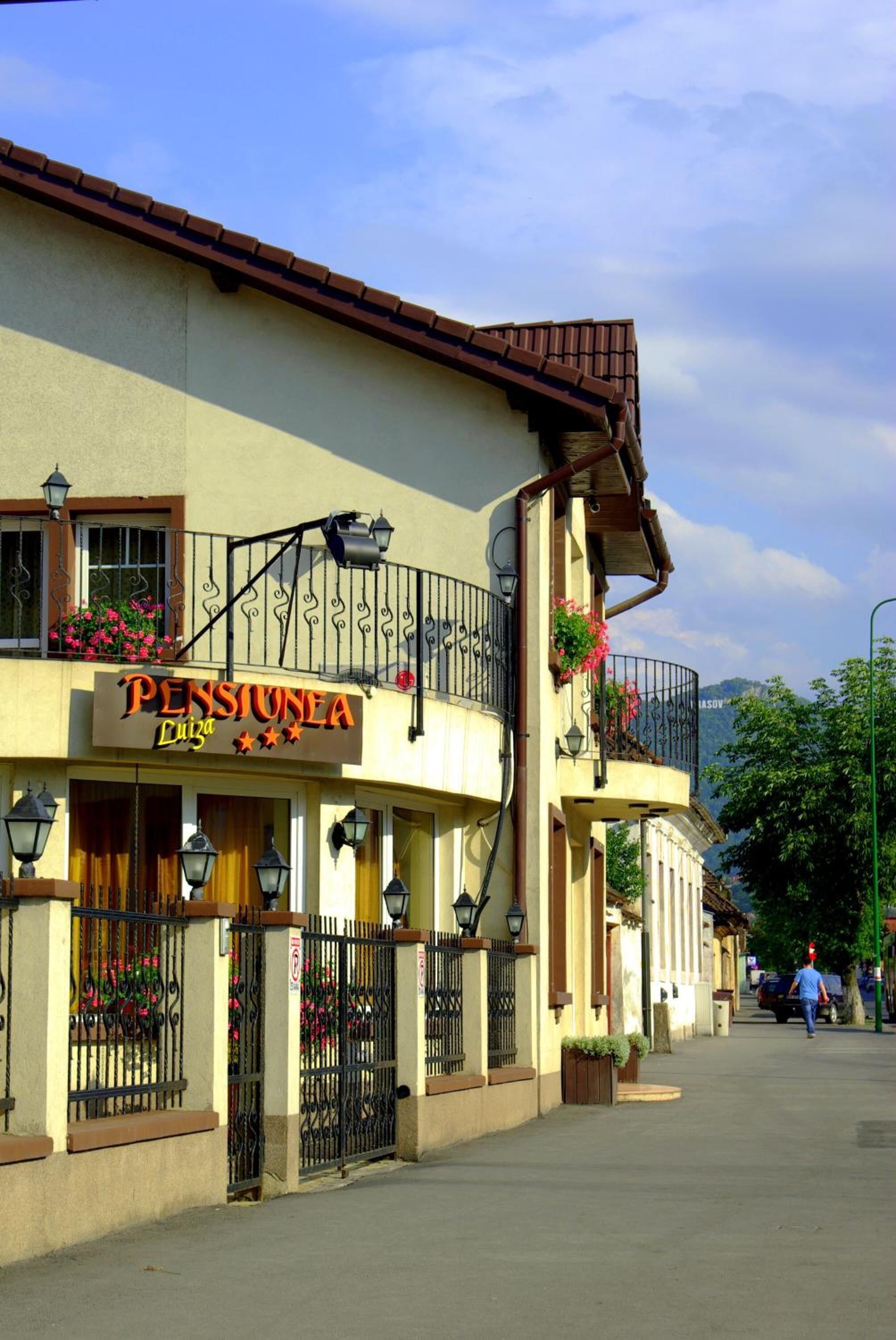 A building with a sign reading "PENSIONE A Luiza" and a balcony with flowers.
