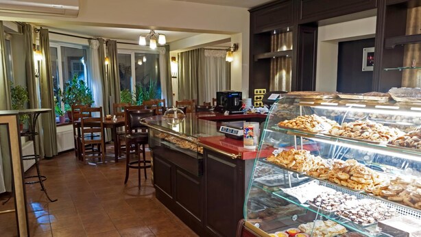 A bakery counter with various pastries and a seating area with chairs and tables. - Pensiunea Luiza (Brasov)