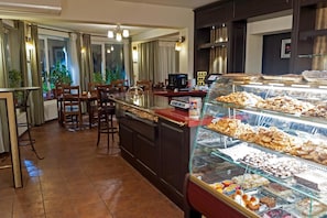 A bakery counter with various pastries and a seating area with chairs and tables. - Pensiunea Luiza (Brasov)