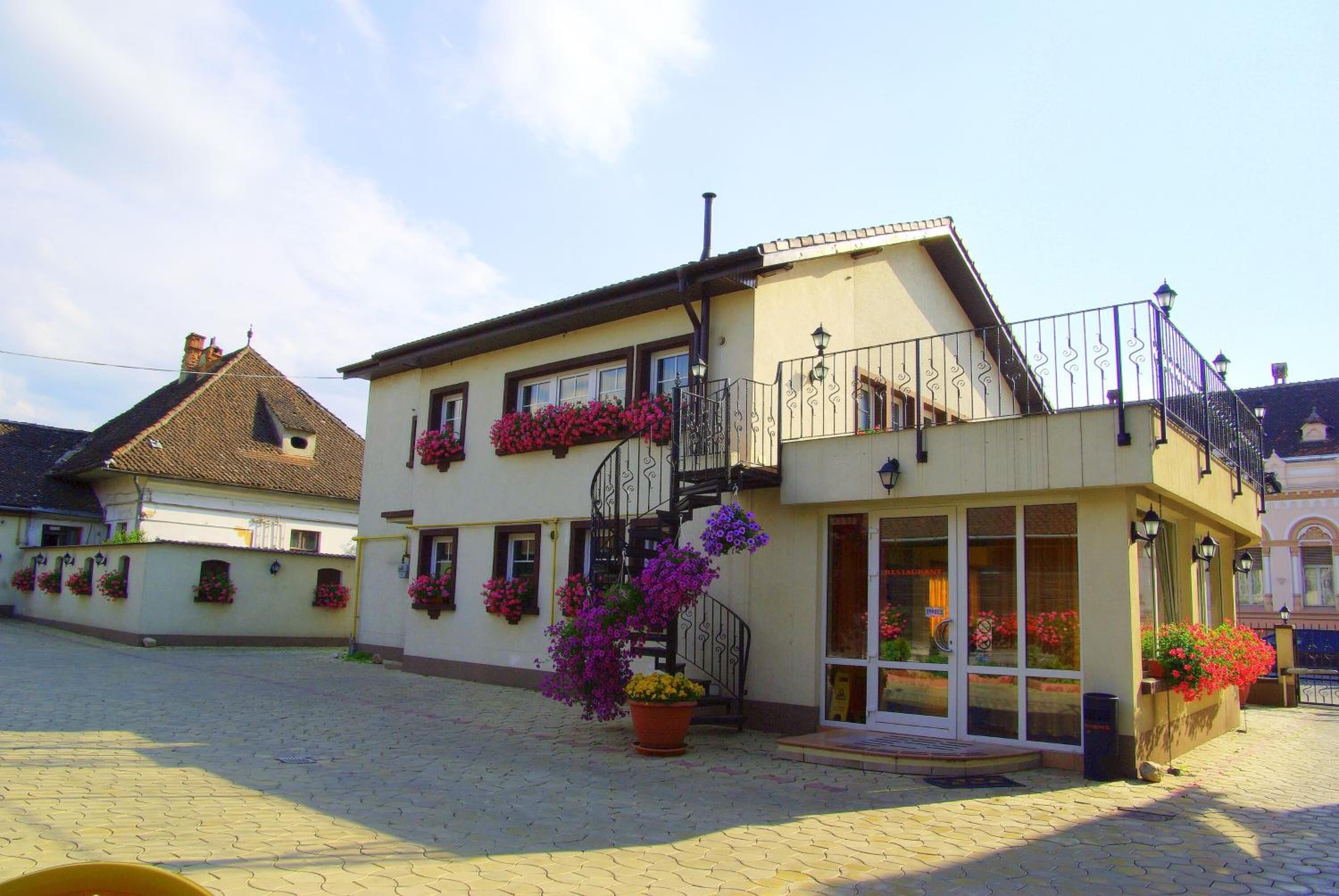 A two-story building with a balcony, flower boxes, and a staircase.