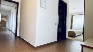 A hotel room with a bed, a small table, and a door leading to another room. - Pensiunea Luiza (Brasov)