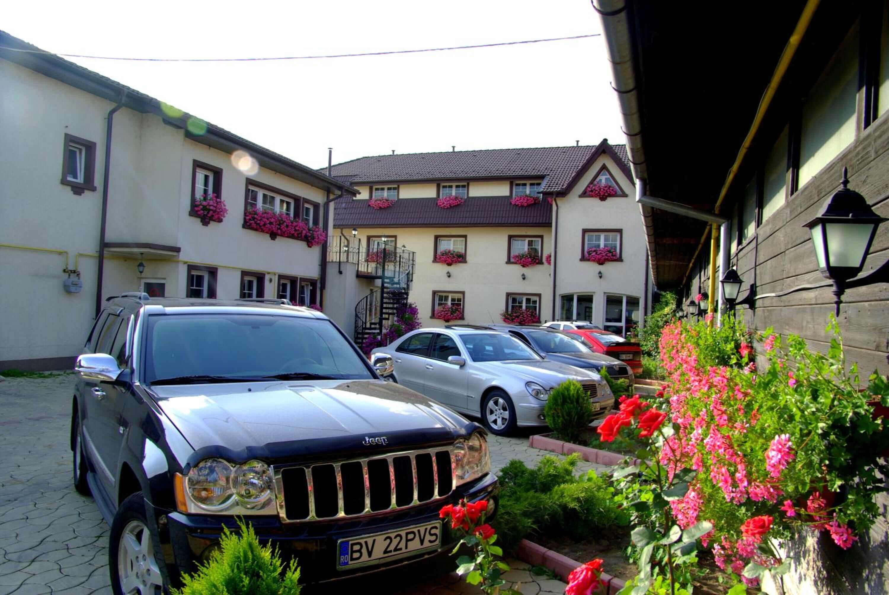 Eine Reihe geparkter Autos vor einem Gebäude mit Blumenkästen an den Fenstern.